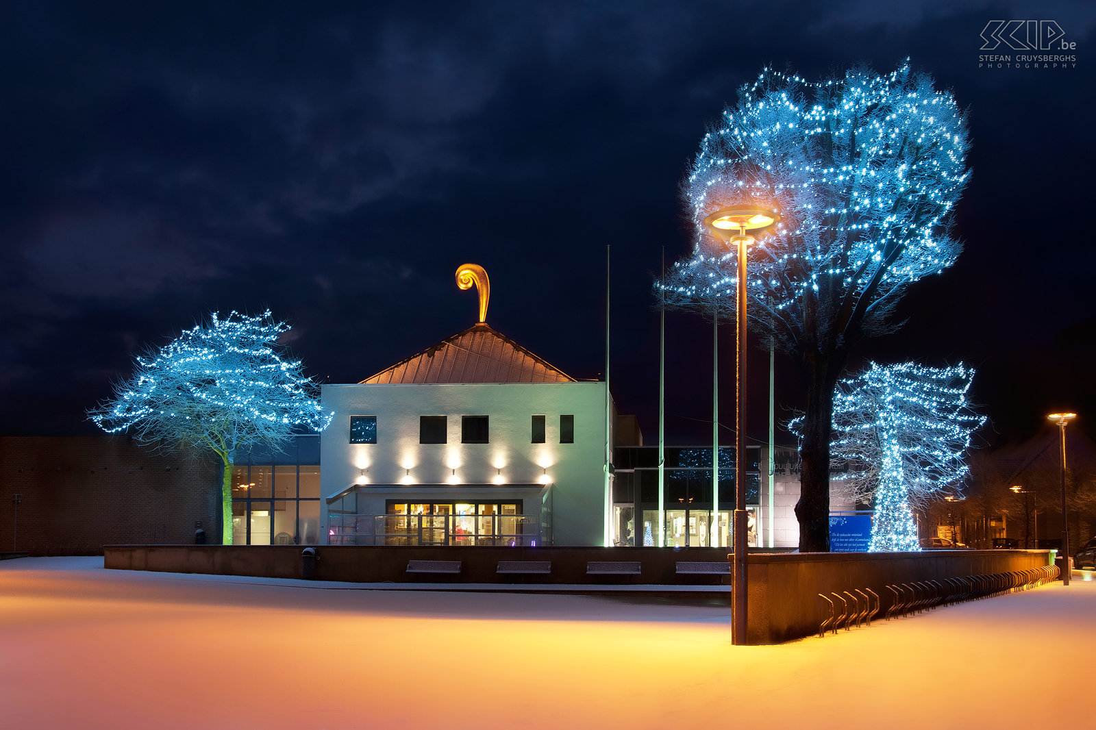 Lommel by night - CC Adelberg After some fresh snowfall in the Christmas week I made a night photo of the cultural center De Adelberg in my hometown Lommel. The building has a golden sculpture on top of the roof which is created by the artist Luk Van Soom. Stefan Cruysberghs